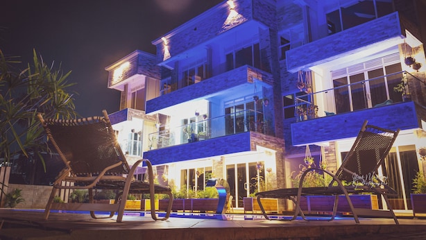 A multi-story building with balconies, outdoor seating, and potted plants. - Kisa apartments (Jinja)