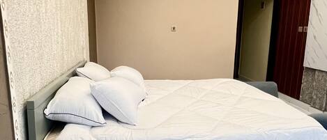 A modern bedroom with a bed, pillows, a nightstand, and a built-in bench.