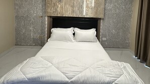 A modern bedroom with a marble-patterned ceiling, a black headboard, and a white bedspread. - Kisa apartments (Jinja)