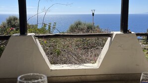 A table with a glass of red wine and a clear view of the sea through a wooden structure. - Bluehorizon (Torre Delle Stelle (Maracalagonis))