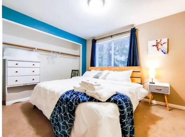 A hotel room with a bed, a bedside table with a lamp, a wardrobe, and a window with curtains.