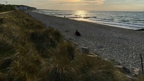 A beach with a clear sky and the sun setting over the water. - Ferienhaus Janeviz 1312 (Kröpelin)
