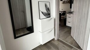 A hallway with a large mirror, a feather artwork, and a door leading to a kitchen area. - Ferienhaus Janeviz 1312 (Kröpelin)