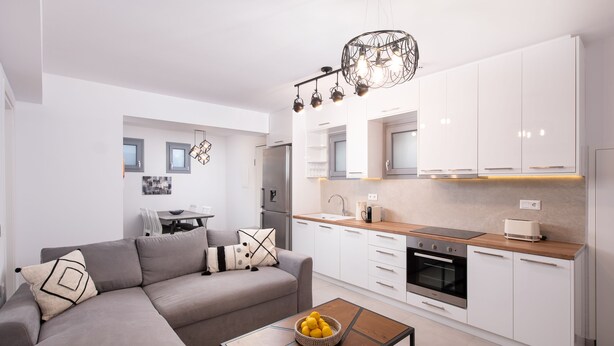 A modern kitchen with white cabinets, a wooden countertop, and a built-in oven. - Hosting Moments Semi Basement Apartment (Mykonos)