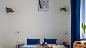 Une chambre d’hôtel bien rangée, avec un lit, des tables de chevet, une carte encadrée de Liverpool et un plateau de petit-déjeuner posé sur le lit.