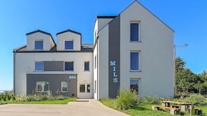 Un bâtiment moderne à deux étages, doté d’un toit plat et d’un petit balcon au dernier étage.