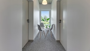 Un couloir avec une fenêtre, deux chaises et une table.