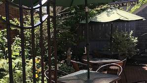 An outdoor patio area with a table and chairs under a green umbrella, surrounded by a metal fence and greenery. - Crow's Nest Newport (Newport)