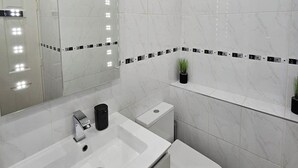 Une salle de bain avec un lavabo blanc, des toilettes et un miroir.