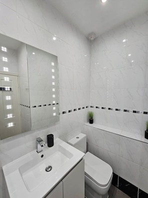 A bathroom with a white sink, a toilet, and a mirror. - Lakeview Court, Sea+Lake view, free parking (Southport)