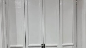A white wardrobe with two doors and a handle in the center. - Lakeview Court Southport (Southport)