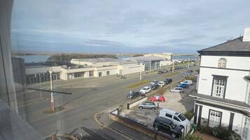 A view of a parking lot with several cars, a building with a white facade, and a clear sky.