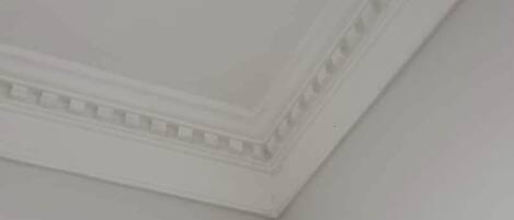 A corner of a room with a plain ceiling and a decorative molding along the ceiling edge.
