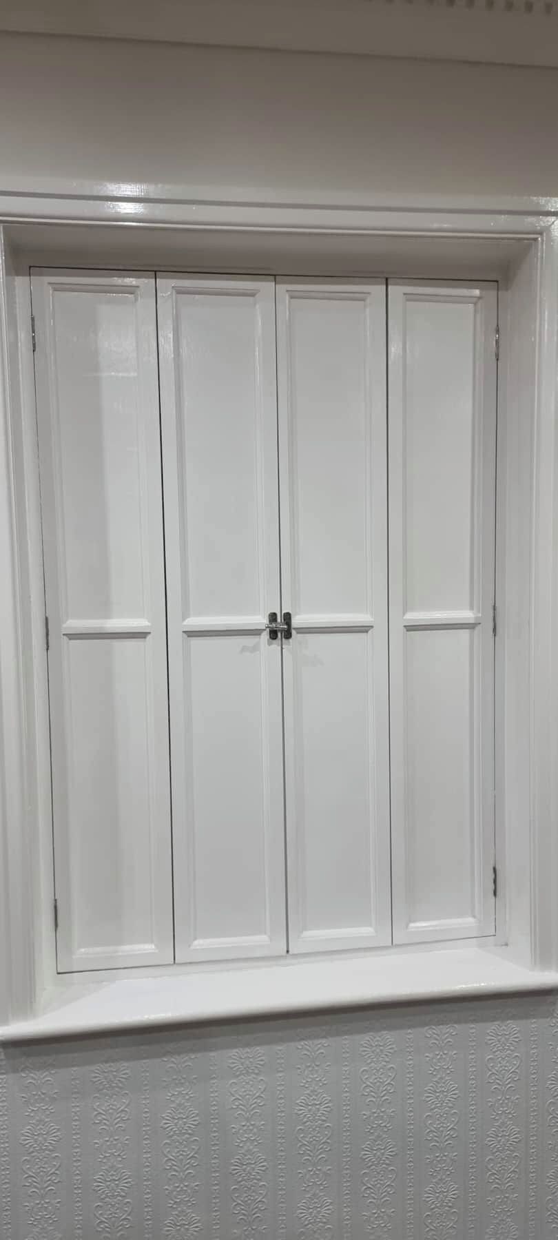 A white wardrobe with two doors and a small window above.