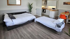 Une chambre avec deux lits, une petite kitchenette et un coin repas.