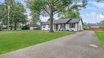 Een gelijkvloers huis met een veranda, oprit en een verzorgd gazon.
