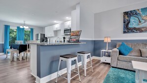 A modern kitchen with white cabinets, a central island with stools, and a dining area with a table and chairs. - Spacious 4BR/2BA home ideal for families, contractors & extended stays. King primary + 3 queen BRs with Smart TVs & mini fridges. Fast WiFi, full kitchen, washer/dryer, backyard & deck. (Clarksville)