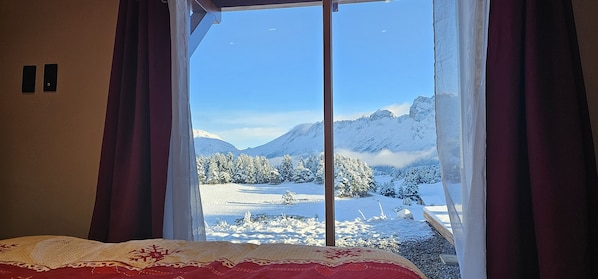A room with a large window overlooking a snowy mountain landscape.