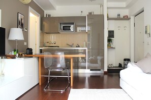 A compact living space with a kitchenette, a dining area, and a sofa.