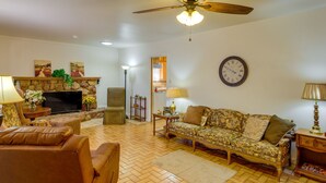 A living room with a fireplace, a sofa, a television, and a ceiling fan. - Phoenix Home w/ Patio: Near Downtown & Light Rail! (Phoenix)