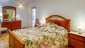 A bedroom with a wooden bed, a dresser, a mirror, and a nightstand with a lamp. - Phoenix Home w/ Patio: Near Downtown & Light Rail! (Phoenix)