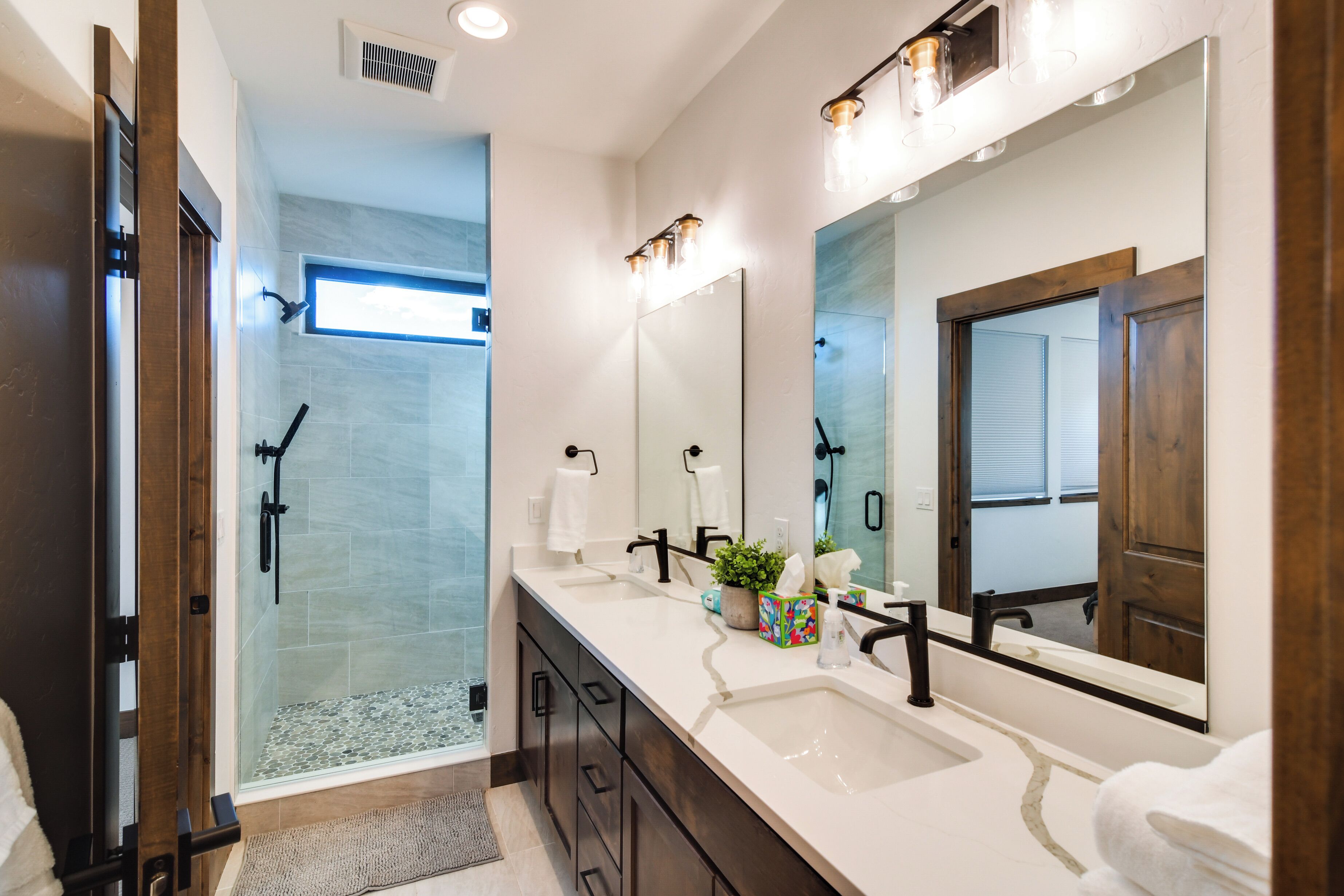 A modern bathroom with a glass shower, a large mirror, and a vanity with a sink and towel rack.