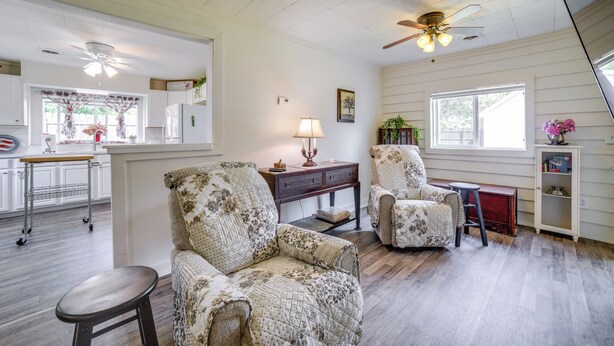 A living room with two patterned armchairs, a wooden coffee table, a small stool, a side table with a lamp, and a cabinet with a flower vase. - Private Plainfield Retreat w/ Gas Grill + Patio (Plainfield)
