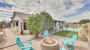 A backyard with a fire pit, two Adirondack chairs, and a swimming pool. - Family-friendly Home w/ Pool & Fire Pit in Peoria (Peoria)