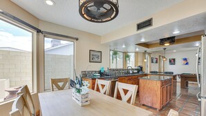 A spacious kitchen with a dining area, featuring a large island, wooden cabinets, and a view to the outside. - Family-friendly Home w/ Pool & Fire Pit in Peoria (Peoria)