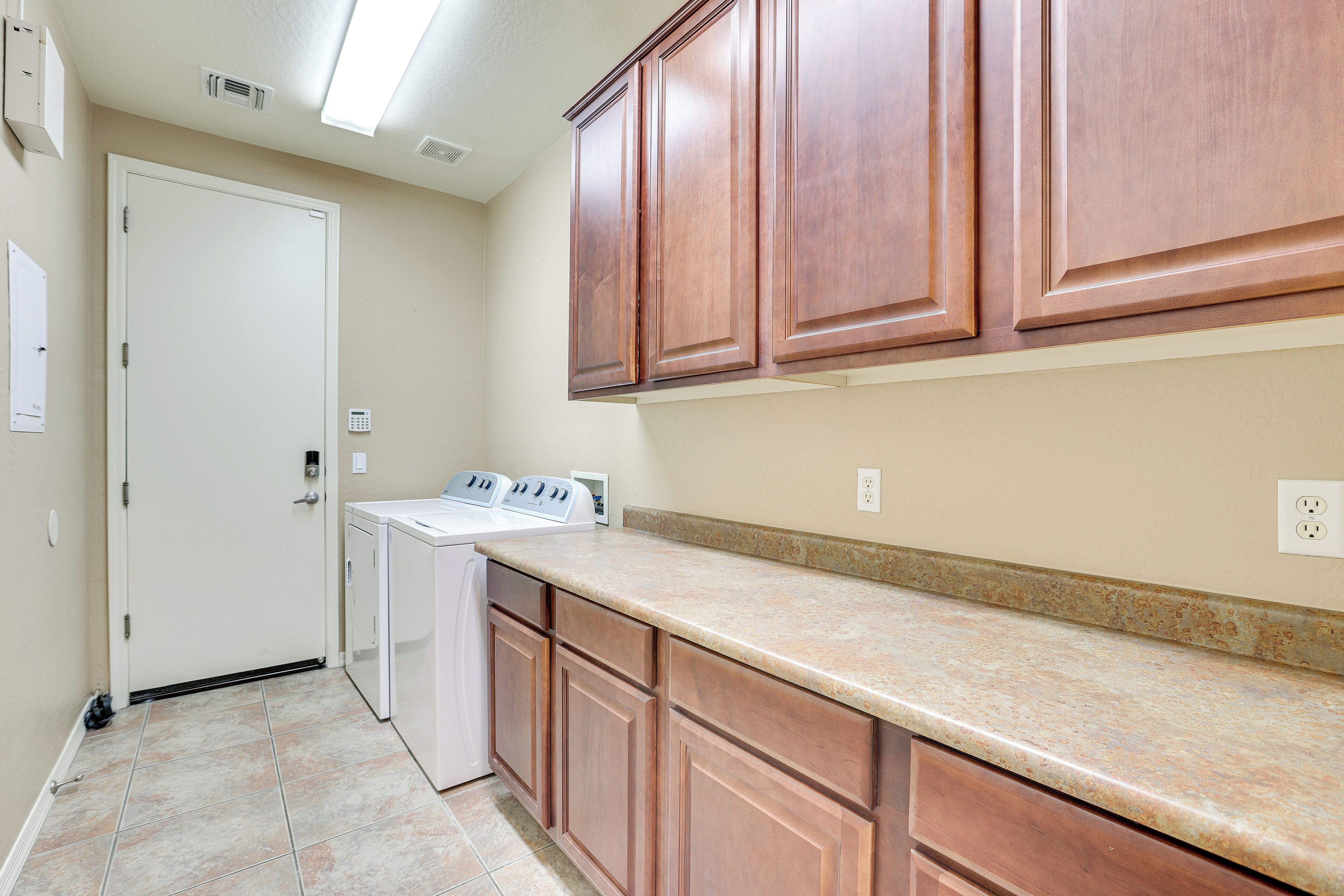 A kitchen with wooden cabinets, a granite countertop, and a washing machine.