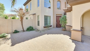 A two-story house with a brick driveway and a palm tree. - Private Pool & Patio at Home Near Goodyear (Litchfield Park)