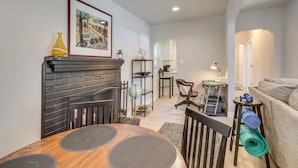 Un salon chaleureux avec une cheminée, une table à manger avec des sets de table, un canapé et un tapis de yoga.