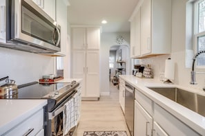 Uma cozinha moderna com armários brancos, eletrodomésticos de aço inoxidável e backsplash com padrão herringbone.