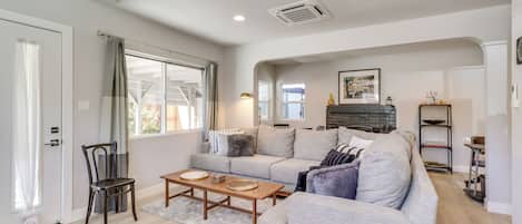 A living room with a sofa, a coffee table, a chair, and a fireplace.