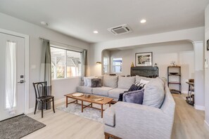 Uma sala de estar moderna com um sofá cinzento, mesa de centro de madeira e lareira.