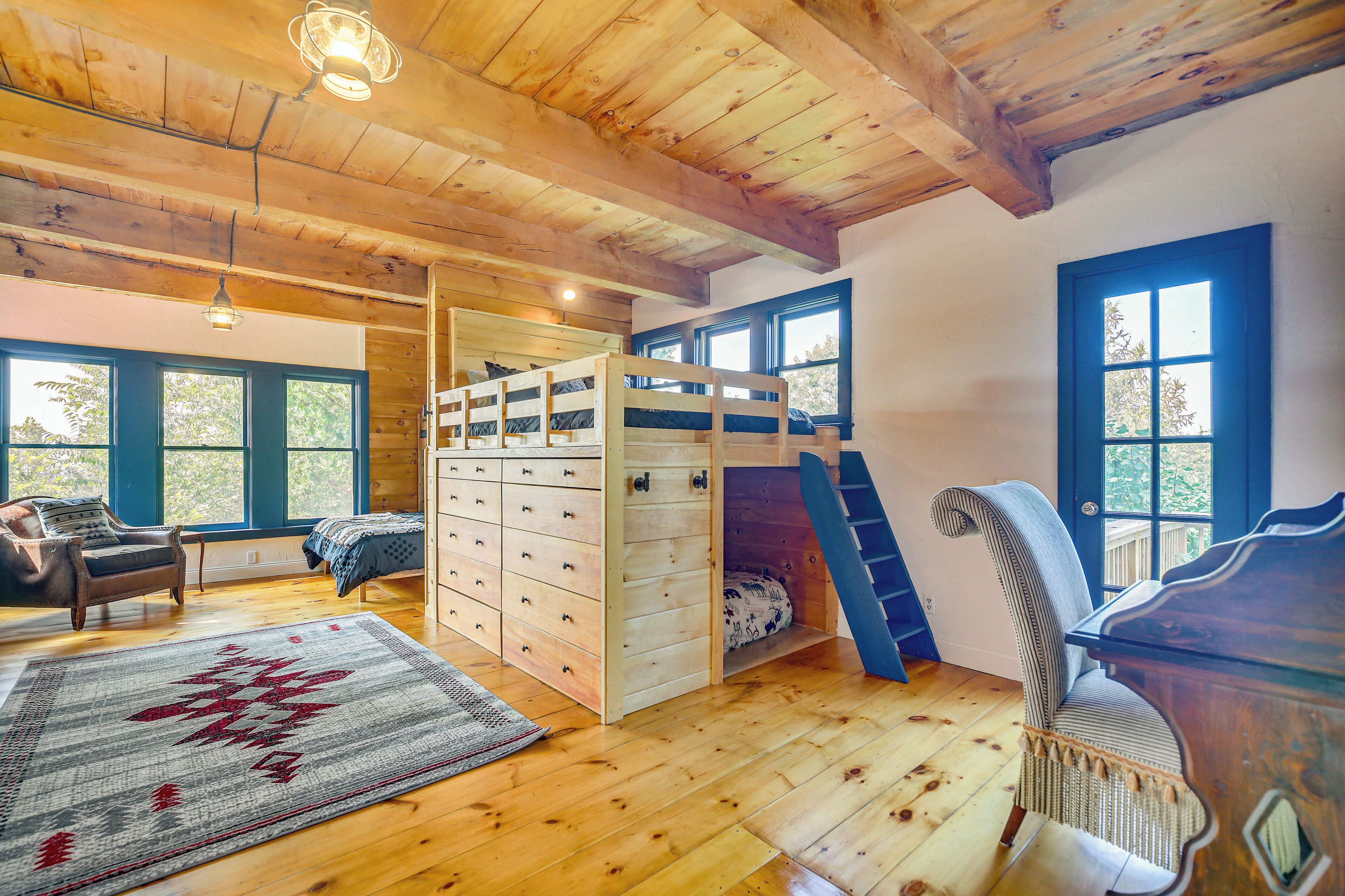 A cozy cabin interior with a bunk bed, wooden floors, a desk, and a chair.