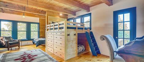 A cozy cabin interior with a bunk bed, wooden floors, a desk, and a chair.