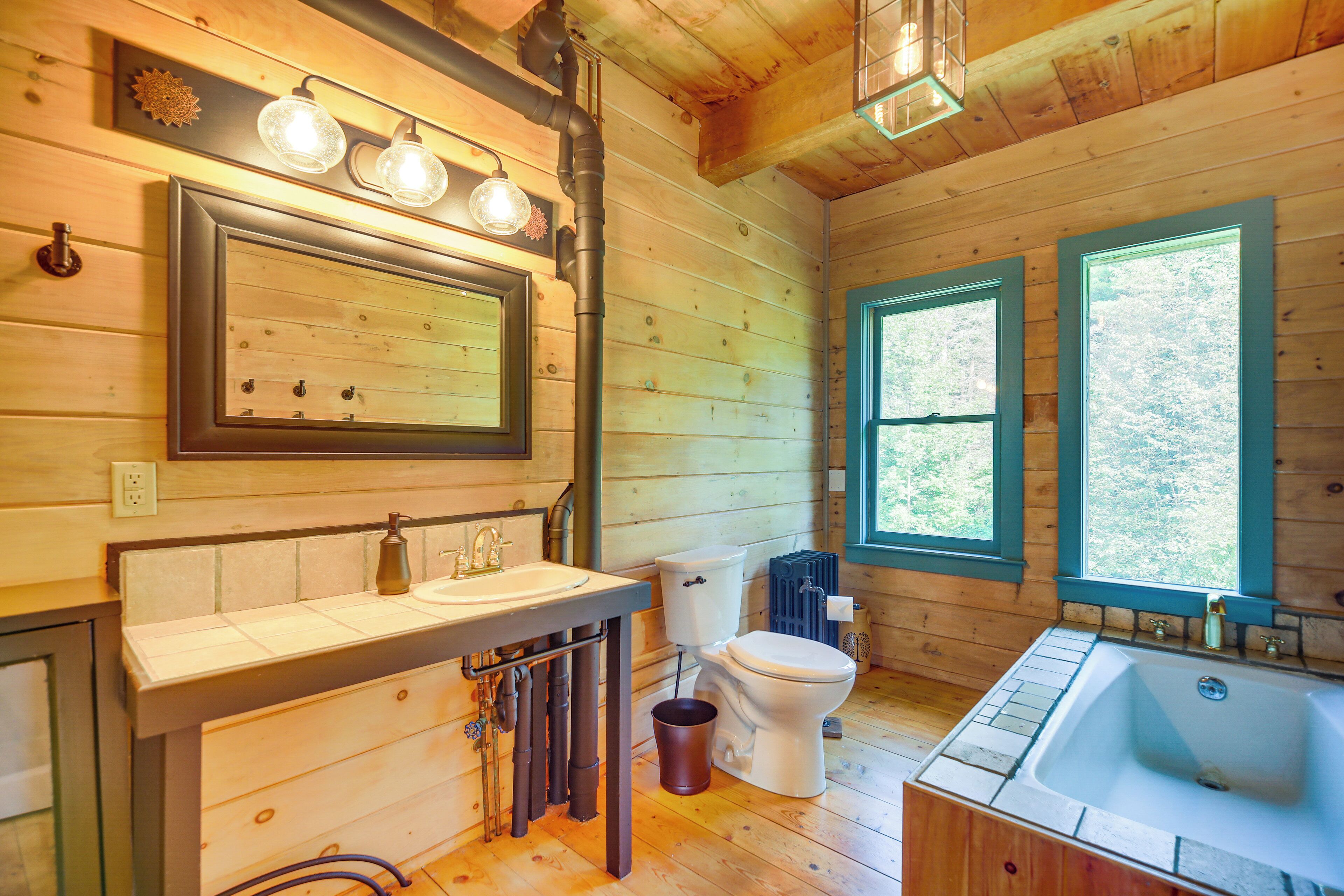 A wooden cabin bathroom with a sink, toilet, and bathtub.