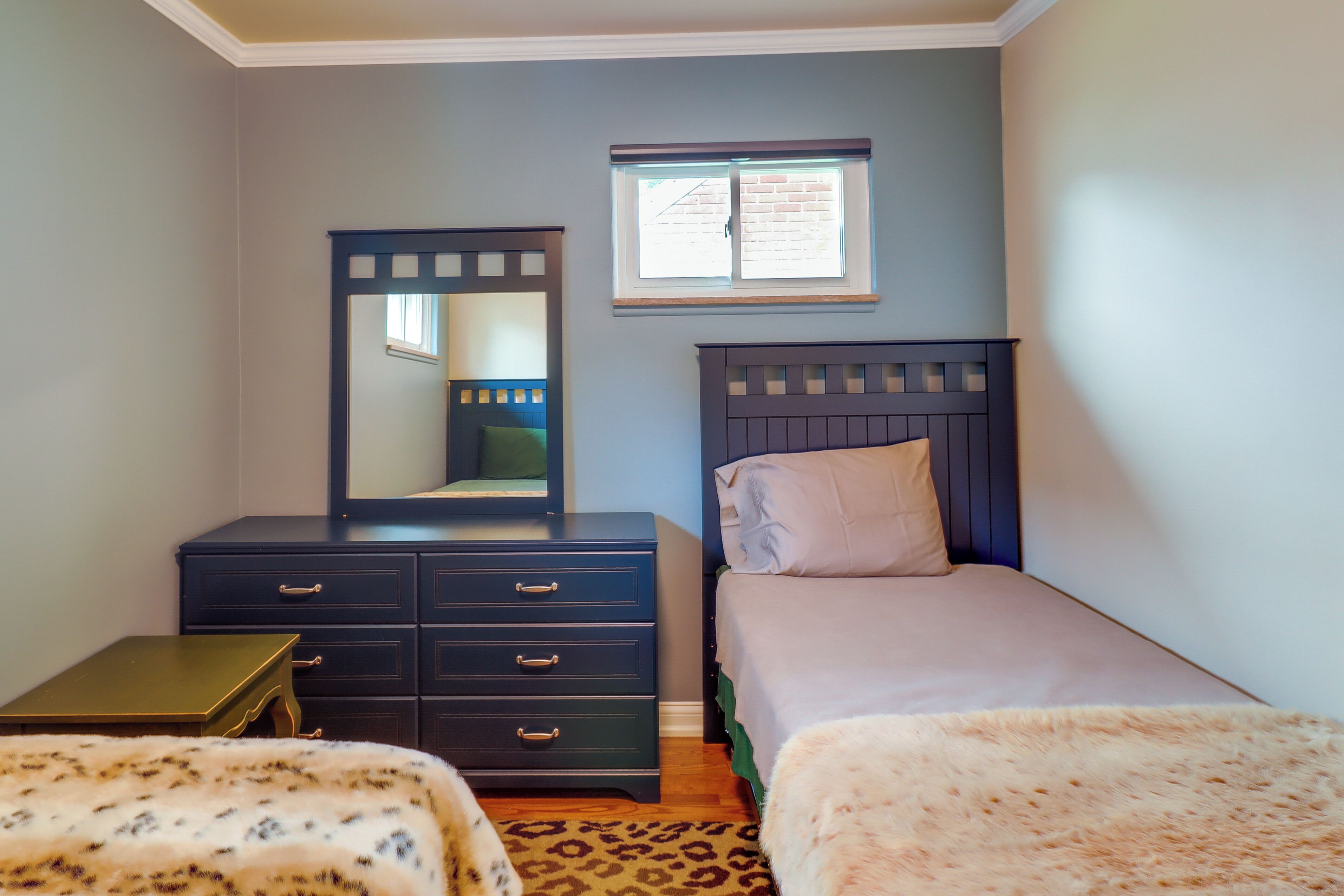 Un dormitorio con cama, cómoda, espejo y ventana.