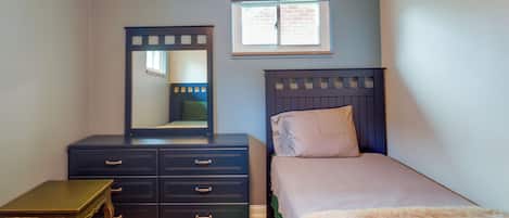 Un dormitorio con cama, cómoda, espejo y ventana.