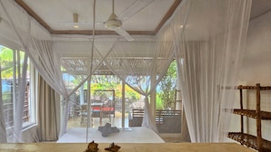 Una stanza con un letto, una ventola a soffitto e vista sull'esterno.