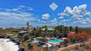 Un resort con piscina, palme e spiaggia.
