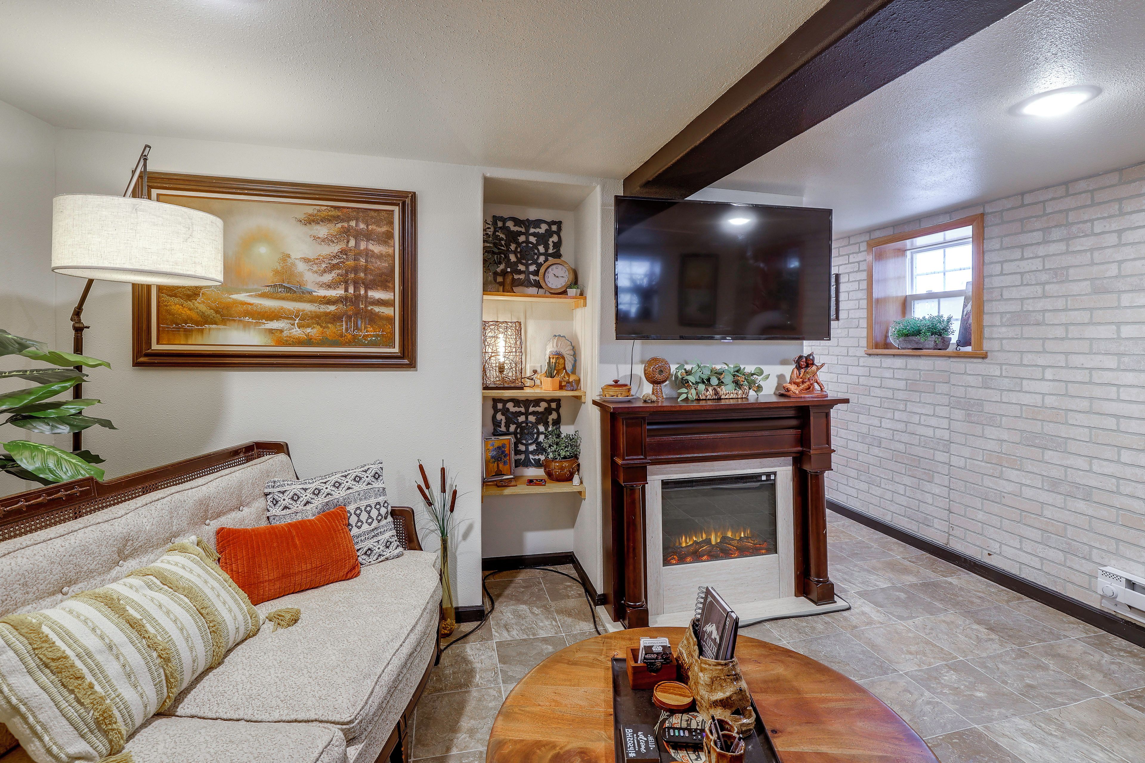 A living room with a sofa, a fireplace, a television, and a painting on the wall.