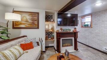 A living room with a sofa, a fireplace, a television, and a painting on the wall.