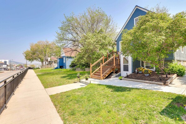 A residential house with a wooden staircase leading to the front door, a well-maintained lawn, and a clear sky. - Black Hills Basecamp: Historic Rapid City Home! (Rapid City)