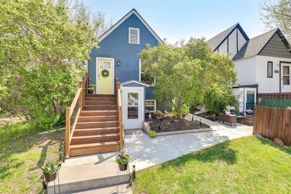 A residential house with a blue exterior, a wooden staircase leading to a front door, and a small front yard with a wooden fence and potted plants. - Black Hills Basecamp: Historic Rapid City Home! (Rapid City)