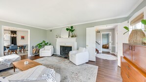 Uma sala de estar espaçosa com lareira, mobiliário branco e um grande armário de madeira.