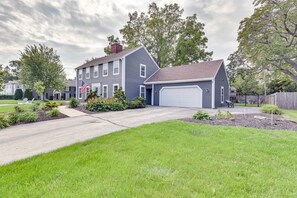 A two-story house with a garage, surrounded by a well-maintained lawn and mature trees.