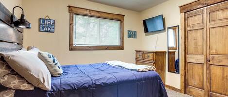 A bedroom with a bed, a dresser, a television, and a wardrobe.