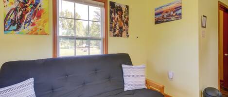 Un salon avec un canapé gris, deux coussins à motifs et trois tableaux accrochés au mur.